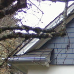 Seamless residential silver gutter wrapping around a roof overhang