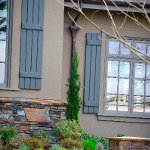 Color matched ornate residential gutter and downspout hidden by shrubbery